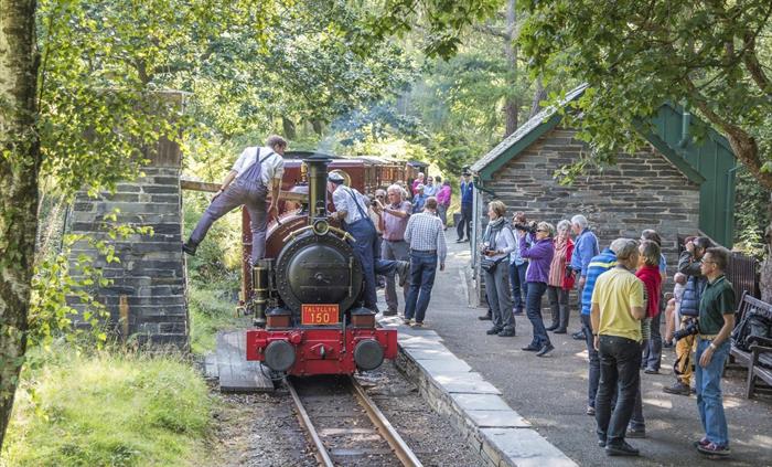 The locomotive takes water at Dolgoch Station with passengers onlooking